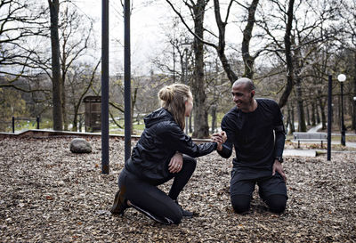 Happy multi-ethnic couple holding hands while exercising in forest