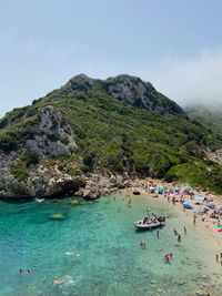 People on beach by mountain against sky