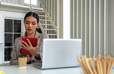 Portrait of young woman using laptop at table