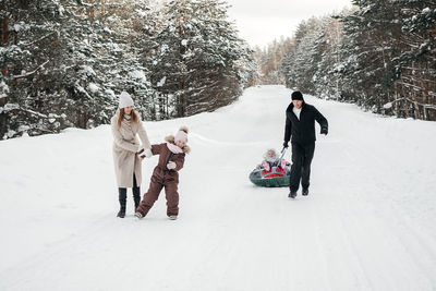 Cheerful family on a weekend rides a sleigh in a snowy forest. high quality photo