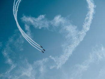 Low angle view of airshow flying against blue sky