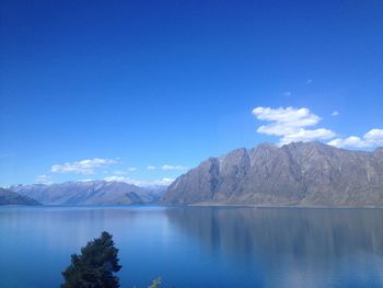 Scenic view of lake and mountains against blue sky