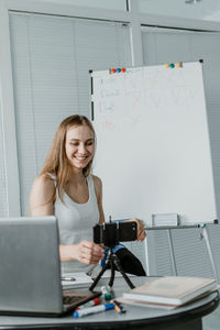 Smiling woman blogging in office