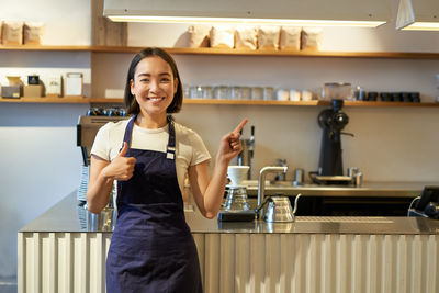 Portrait of young woman standing in kitchen