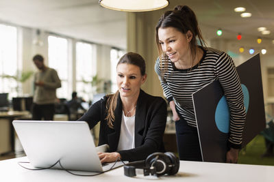 Businesswomen discussing over laptop in creative office