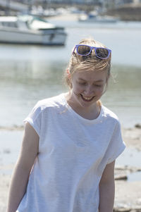 Smiling young woman standing at beach on sunny day