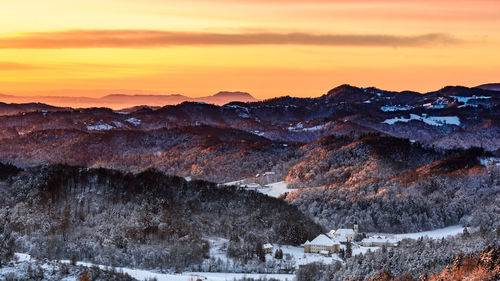 Scenic view of snowcapped mountains against orange sky