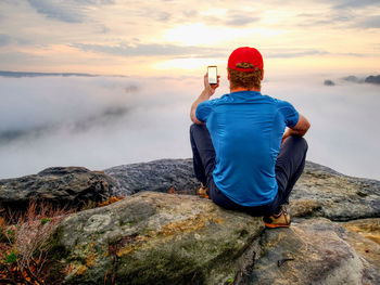 Man taking picture of amazing fall mountains on his phone in misty weather