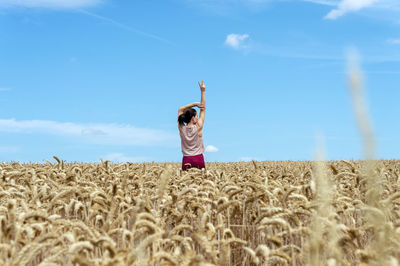 Rear view of woman standing on field against sky