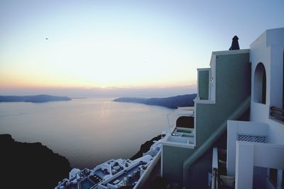 Sea by buildings against sky during sunset