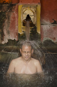 Shirtless monk taking bath in hot spring at temple