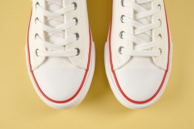 Pair of trendy shoes on yellow background