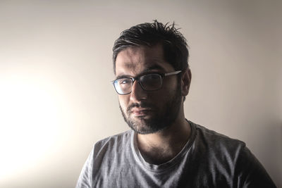 Portrait of young man wearing eyeglasses against gray background