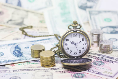 Close-up of pocket watch amidst currency