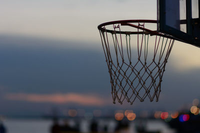 Close-up of basketball hoop against sky during sunset