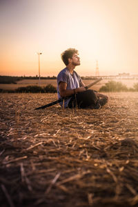 Man sitting on field against clear sky