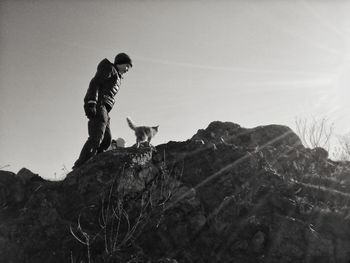 Boy with cat standing on rock against sky