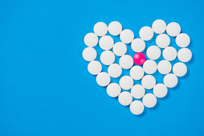 Close-up of pills arranged in heart shape against blue background