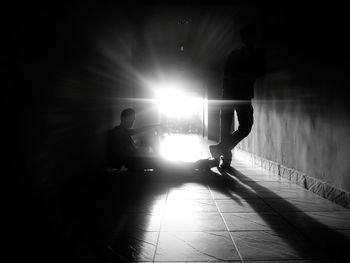 Silhouette people standing on floor against bright sun