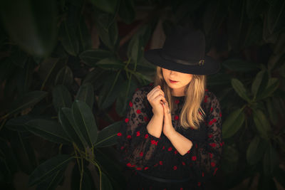 Portrait of young woman standing against plants