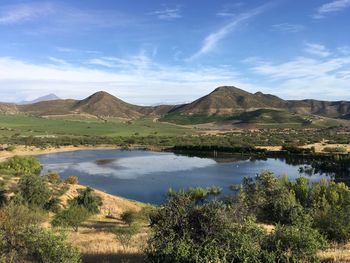 Scenic view of lake by mountains against sky