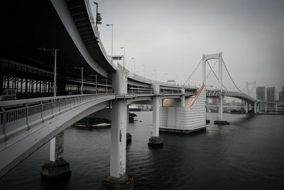 Bridge over river in city against sky