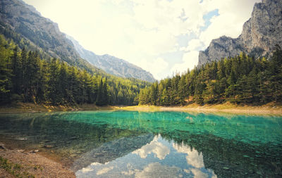 Reflection of rocky mountains in lake against cloudy sky