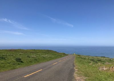 Road by sea against blue sky