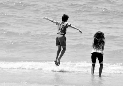 Rear view of people playing at beach