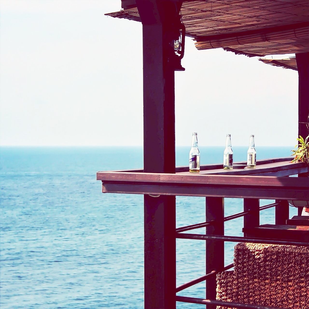 sea, water, clear sky, horizon over water, built structure, architecture, indoors, pier, architectural column, sunlight, day, column, copy space, nature, railing, sky, no people, tranquility, wood - material