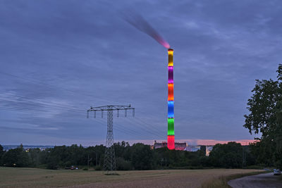 Electricity pylon by trees against blue sky