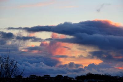 Silhouette of buildings against cloudy sky at sunset