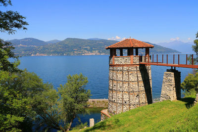 Built structure by lake against clear blue sky