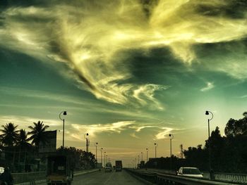 Road in city against sky at sunset