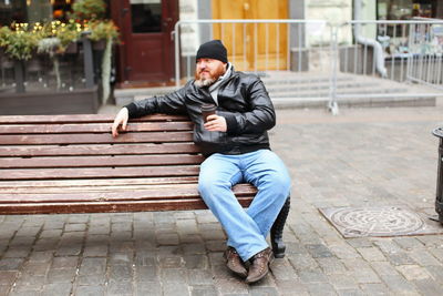 Man having drink while sitting on bench a