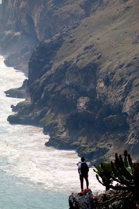 Man standing on cliff by sea