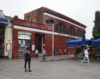 People walking on footpath against buildings in city