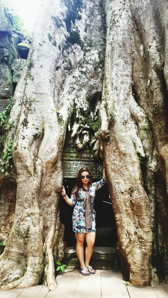 looking at camera, tree, tree trunk, front view, portrait, casual clothing, young adult, person, lifestyles, standing, full length, smiling, young women, leisure activity, low angle view, day, outdoors, three quarter length