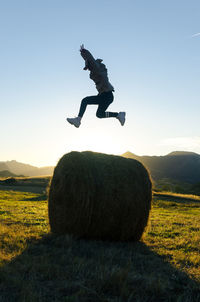 Man jumping on top of hay bale in sunlight