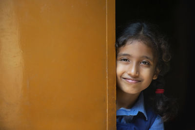 Portrait of smiling girl standing by door