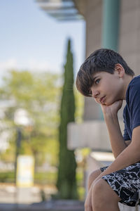 Serious boy thinking over a problem and contemplating sitting on a fence. real people concept.