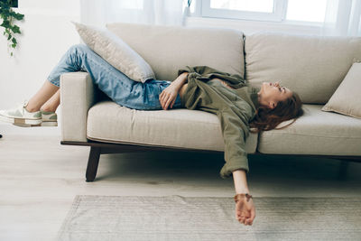 Low section of woman sitting on sofa at home