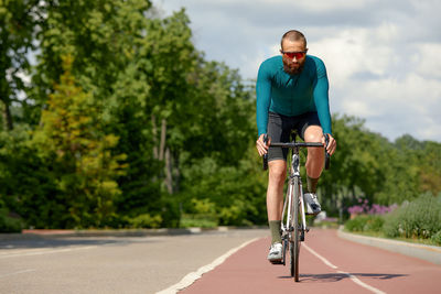 Rear view of man riding bicycle on road