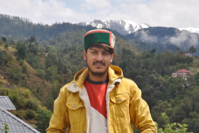 A north indian young men standing outdoor against beautiful mountains.