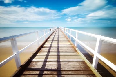 Wooden bridge over sea against sky