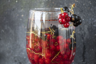 Red and black currant in the wineglass on the gray and blue background. large group of colorful