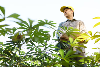 Young man standing by plants against sky