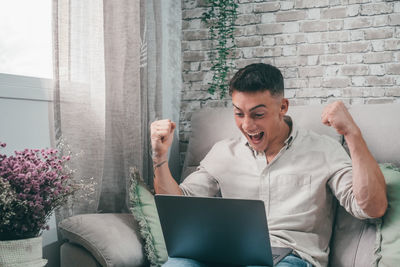 Young woman using laptop while sitting on sofa at home