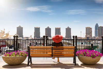 Rear view of woman sitting on bench in city