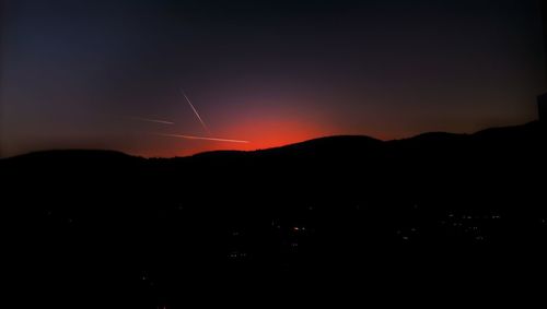 Scenic view of silhouette mountains against orange sky